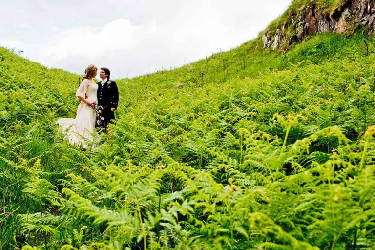 couple embrace surrounded by green ferns